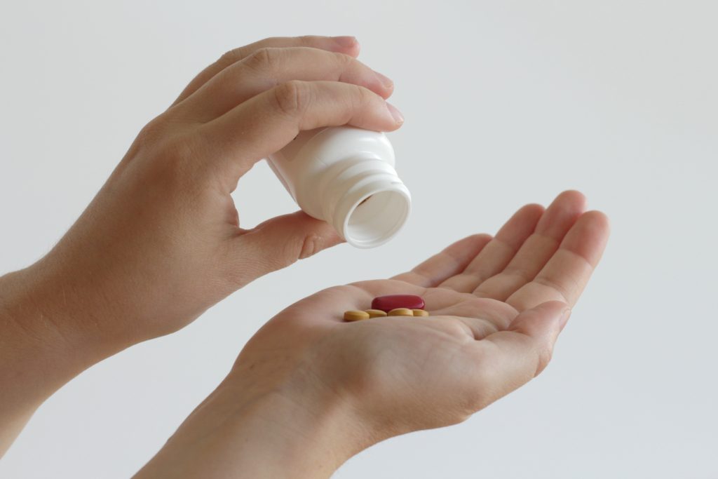 pouring out pills into hand from a plastic container